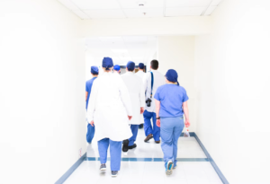 A team of doctors walk down an empty hallway leading to another area.