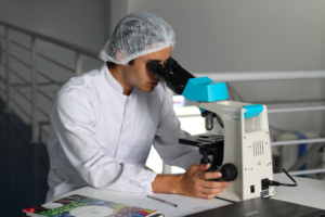 A healthcare technician in a lab looks into his microscope.